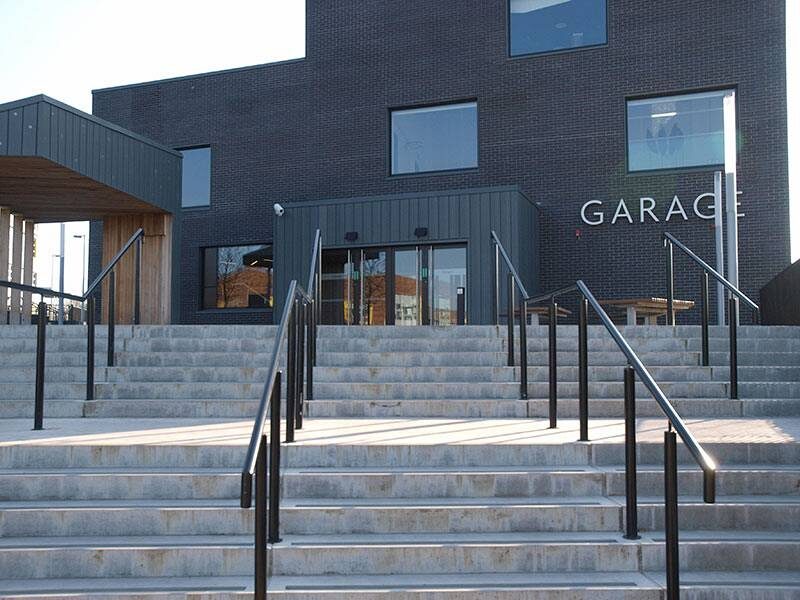 A modern building with dark brick exterior and large windows, labeled